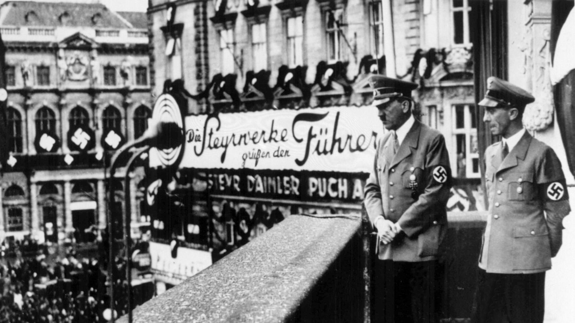 Der Führer und Reichskanzler Adolf Hitler (l) schaut mit Propagandaminister Dr. Joseph Goebbels am 14. März 1938, einen Tag nach dem Einmarsch der deutschen Wehrmacht in Österreich, vom Balkon des Hotels Imperial in Wien am Schwarzenbergplatz auf die ihm
