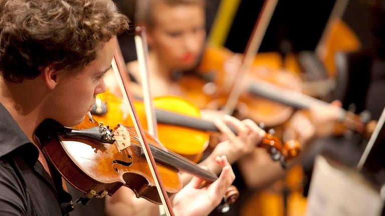 Ein junger Mann spielt inmitten eines jungen Orchesters. Ein junger Mann spielt inmitten eines jungen Orchesters.