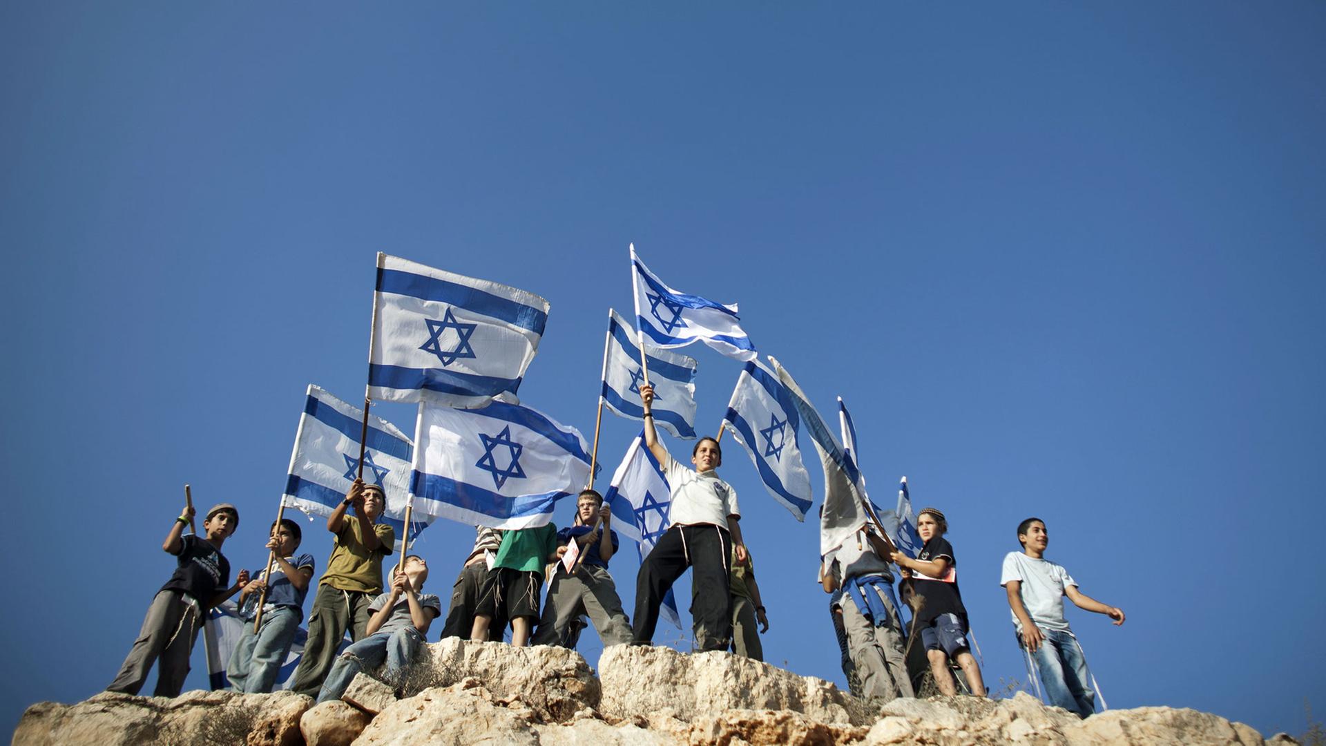 Junge Siedler stehen israelische Fahnen schwenkend auf einem Hügel, um gegen die anstehende Anerkennung Palästinas durch die Vereinten Nationen zu demonstrieren. Junge Siedler stehen israelische Fahnen schwenkend auf einem Hügel, um gegen die anstehende Anerkennung Palästinas durch die Vereinten Nationen zu demonstrieren.