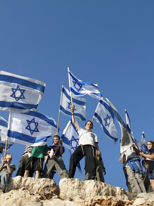 Junge Siedler stehen israelische Fahnen schwenkend auf einem Hügel, um gegen die anstehende Anerkennung Palästinas durch die Vereinten Nationen zu demonstrieren.