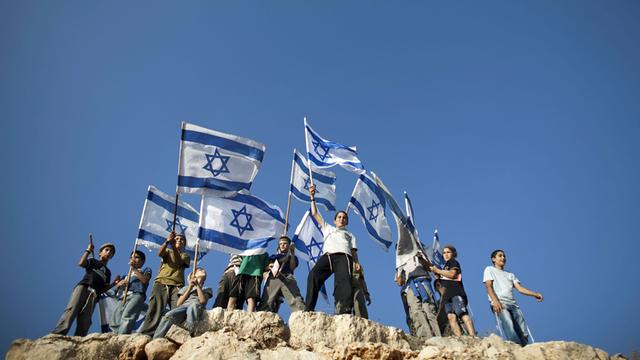 Junge Siedler stehen israelische Fahnen schwenkend auf einem Hügel, um gegen die anstehende Anerkennung Palästinas durch die Vereinten Nationen zu demonstrieren.