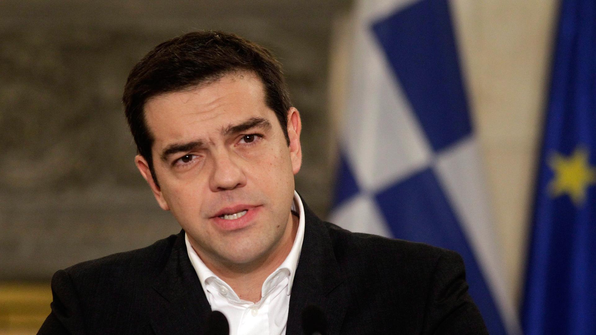 Alexis Tsipras bei einer Pressekonferenz an einem Rednerpult, im Hintergrund die griechische Fahne. Alexis Tsipras bei einer Pressekonferenz an einem Rednerpult, im Hintergrund die griechische Fahne.