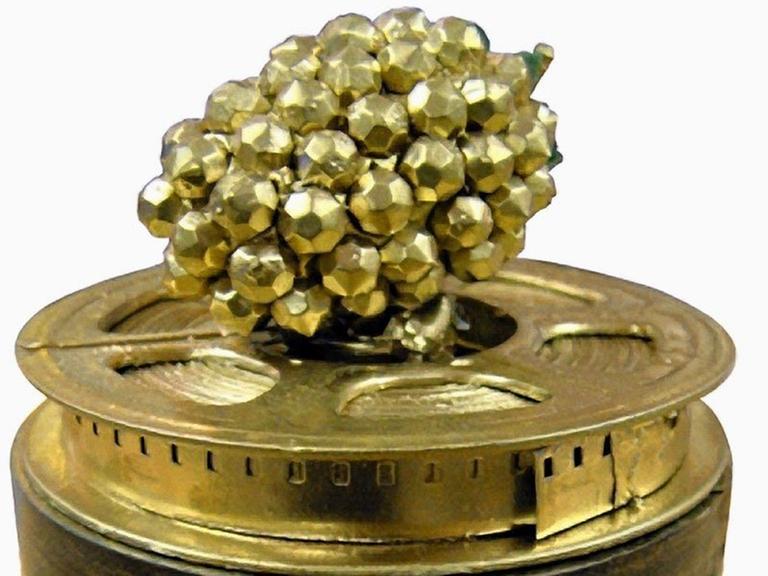 Das Bild zeigt den Anti-Filmpreis "Golde Himbeere". Er besteht aus der namensgebenden Frucht in goldener Farbe, die sich auf einer golden Filmrolle befindet.