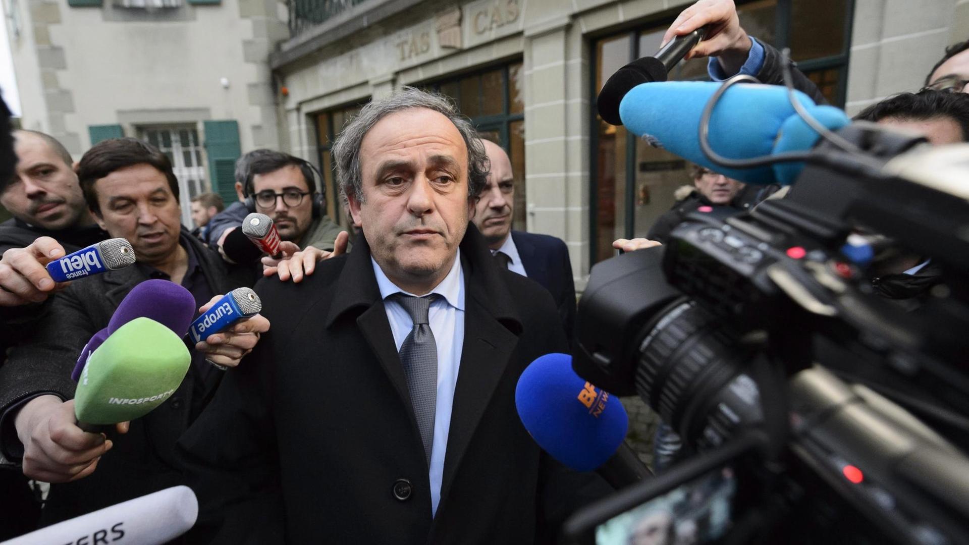 Michel Platini ist umringt von Reportern mit Mikrofonen und Kameras. Michel Platini ist umringt von Reportern mit Mikrofonen und Kameras.