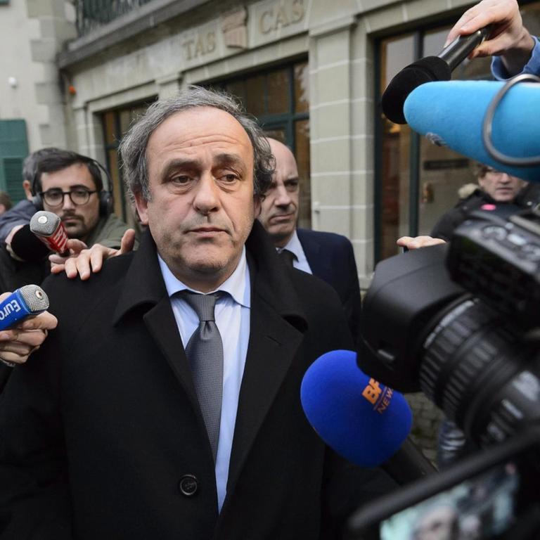 Michel Platini ist umringt von Reportern mit Mikrofonen und Kameras.