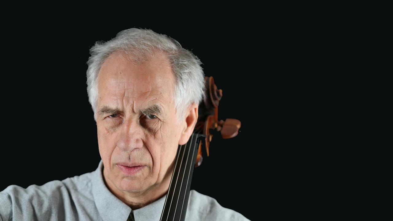Ein Mann blickt ernst in die Kamera. Neben seinem Kopf sieht man die Schnecke seines Violoncellos. Es ist der Cellist Wolfgang Boettcher. Ein Mann blickt ernst in die Kamera. Neben seinem Kopf sieht man die Schnecke seines Violoncellos. Es ist der Cellist Wolfgang Boettcher.