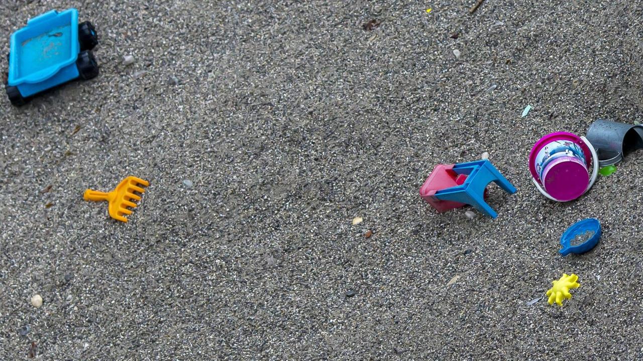 Verstreutes Spielzeug in einem Sandkasten ohne Kinder Verstreutes Spielzeug in einem Sandkasten ohne Kinder