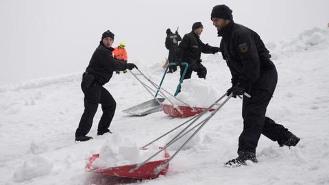 Polizisten räumen Schnee vom Dach der Eissporthalle in Berchtesgaden.
