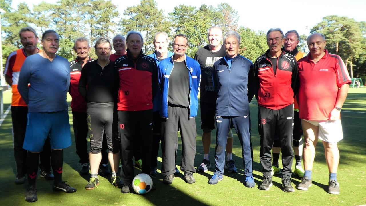 Ältere Männer stehen auf einem Fußballfeld zu einem Gruppefoto zusammen. Ältere Männer stehen auf einem Fußballfeld zu einem Gruppefoto zusammen.