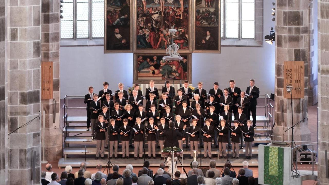 Ein Knabenchor steht im Altarraum einer großen Kirche und singt. Ein Knabenchor steht im Altarraum einer großen Kirche und singt.