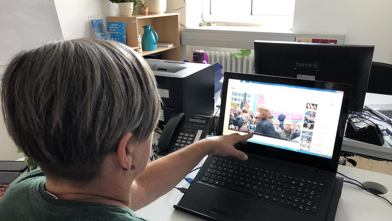 Ausstiegshelferin Petra Franetzki zeigt mit dem Finger auf einen Laptop, auf dem Videos von Naziaufmärschen laufen.