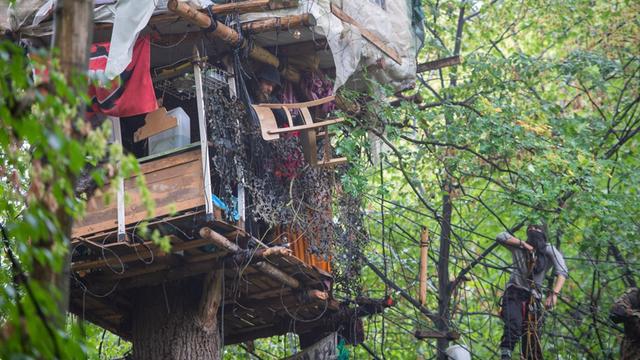 06.09.2018: Nordrhein-Westfalen, Kerpen: Ein Umweltaktivist auf einem Baumhaus im Hambacher Forst hält einen Stuhl aus dem Fenster. Die Polizei und der Energiekonzern RWE führen die Räumungsarbeiten im Hambacher Forst fort