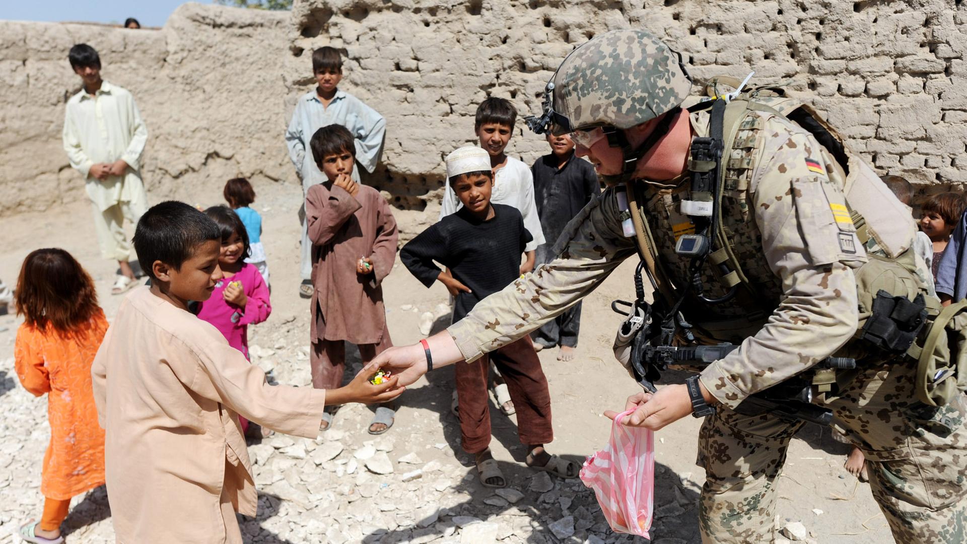 Bundeswehrsoldaten verteilen im Distrikt von Charah Darreh nahe Kundus während einer Patroillle Bonbons an Kinder. Die Soldaten suchten nach versteckten Sprengfallen und deren Urhebern. (August 2011) Bundeswehrsoldaten verteilen im Distrikt von Charah Darreh nahe Kundus während einer Patroillle Bonbons an Kinder. Die Soldaten suchten nach versteckten Sprengfallen und deren Urhebern. (August 2011)
