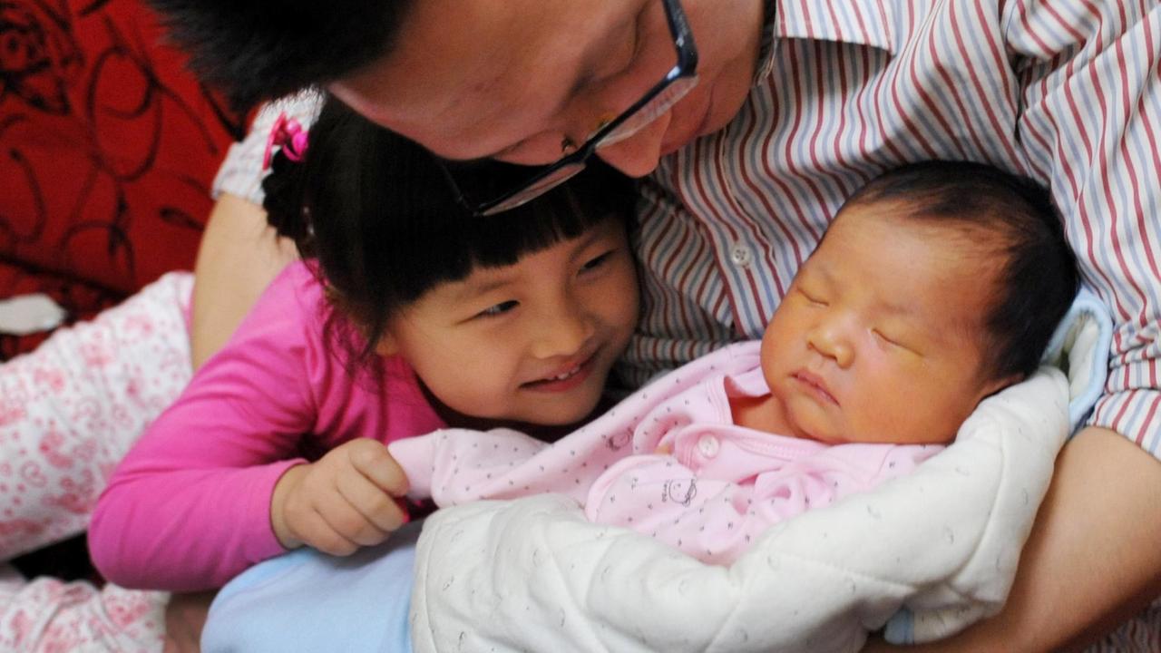 Ein chinesischer Vater mit einem Baby und einem Kleinkind. Ein chinesischer Vater mit einem Baby und einem Kleinkind.