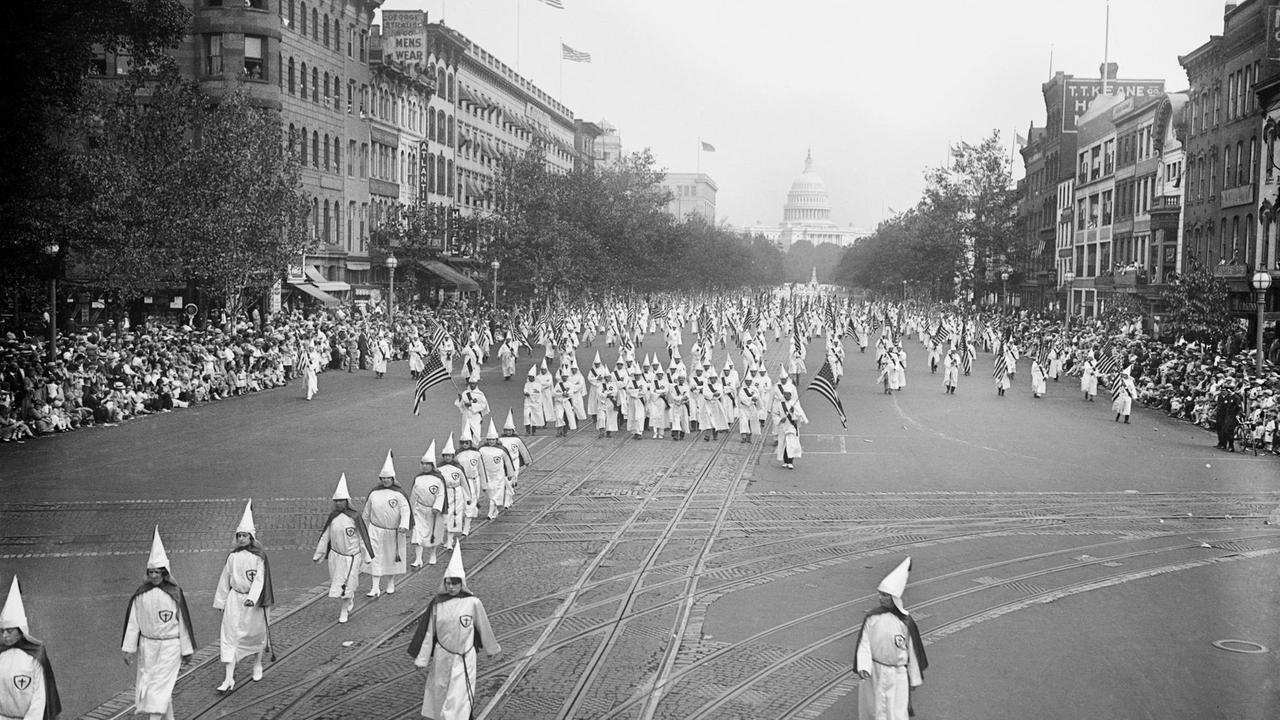 Historische Fotografie von Mitgliedern des Ku-Klux-Klans, die während einer Parade die Pennsylvania Avenue hinuntermarschieren.
