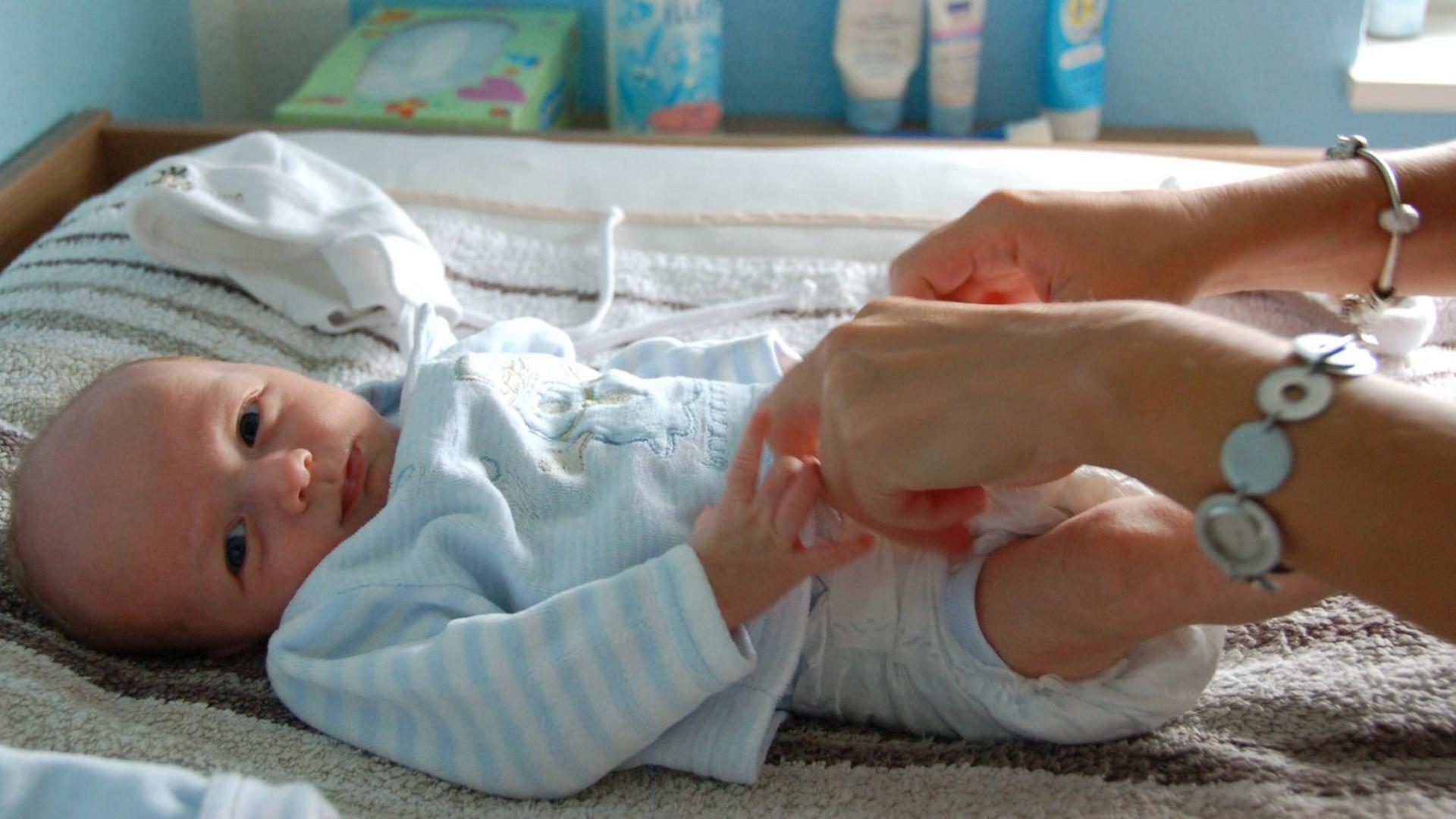 Mutter wickelt ihren fünf Monate alten Säugling Mutter wickelt ihren fünf Monate alten Säugling