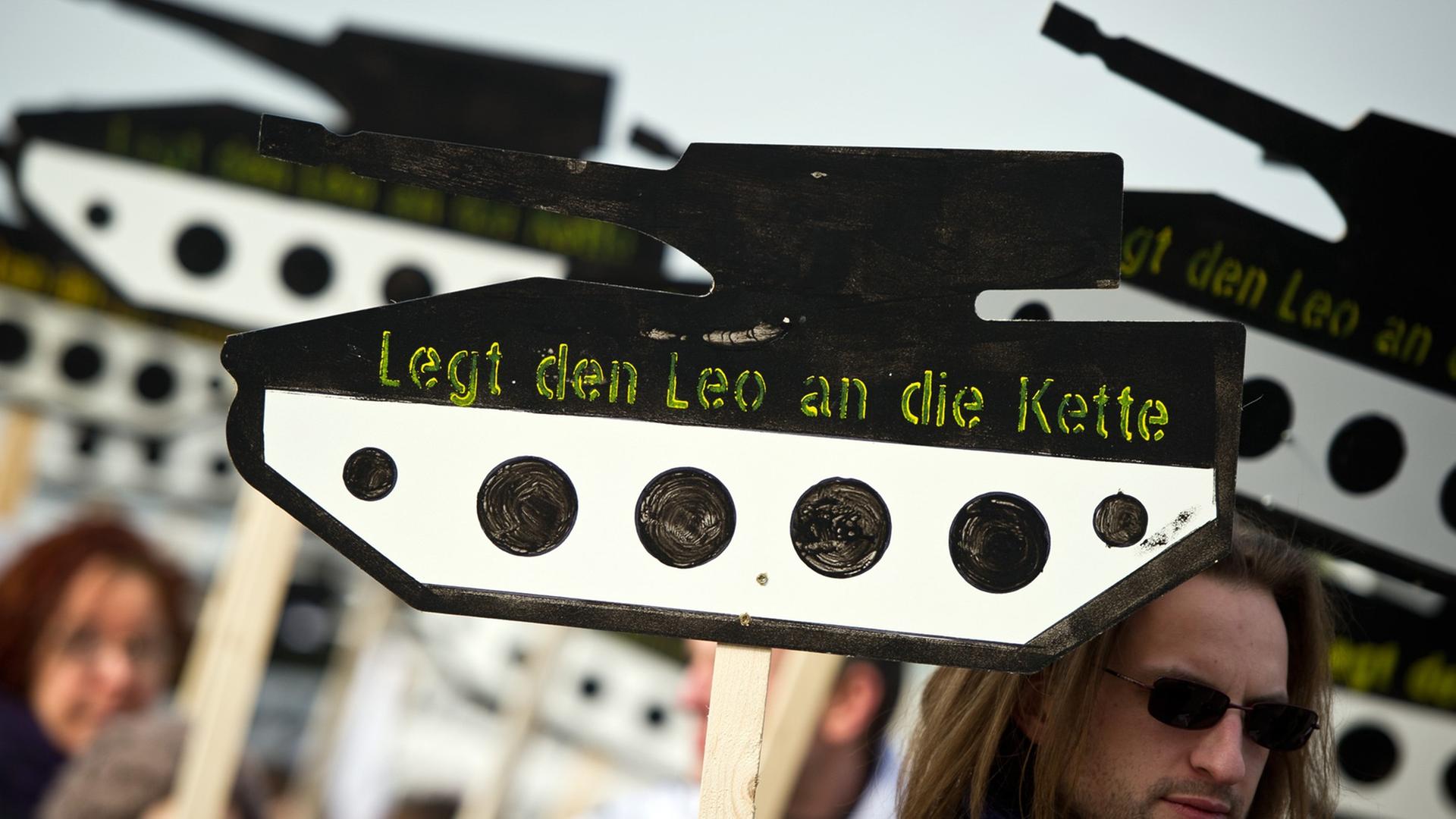 Ein Demonstrant trägt ein Schild in Form eines Panzers aus Holz mit der Aufschrift "Legt den Leo an die Kette" Ein Demonstrant trägt ein Schild in Form eines Panzers aus Holz mit der Aufschrift "Legt den Leo an die Kette"