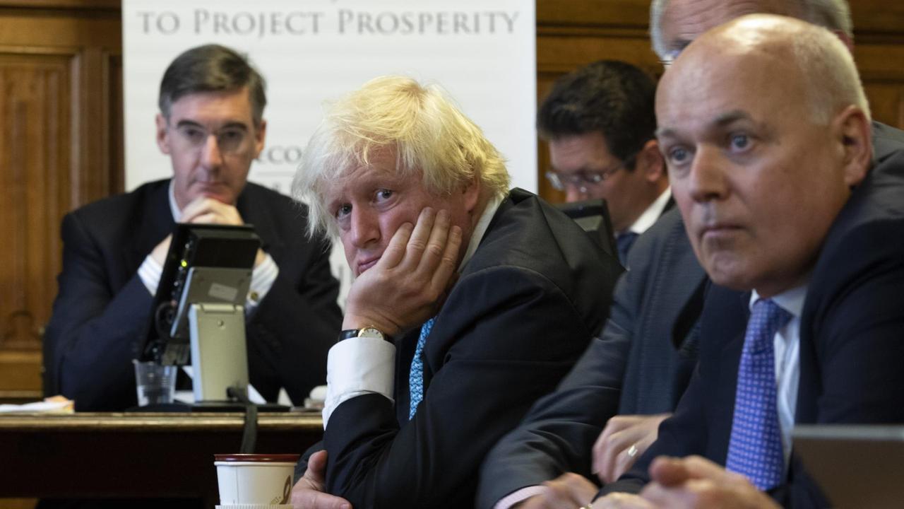 Boris Johnson stützt seinen Kopf auf die Hand und schaut müde an der Kamera vorbei. Um ihn herum unterschiedliche Personen, u.a. Jacob Rees Mogg. Boris Johnson stützt seinen Kopf auf die Hand und schaut müde an der Kamera vorbei. Um ihn herum unterschiedliche Personen, u.a. Jacob Rees Mogg.