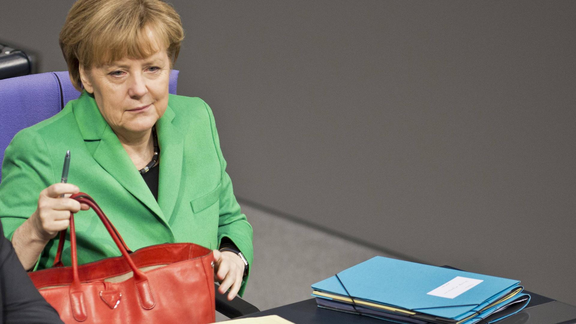 Bundeskanzlerin Angela Merkel im grünen Blazer mit roter Tasche