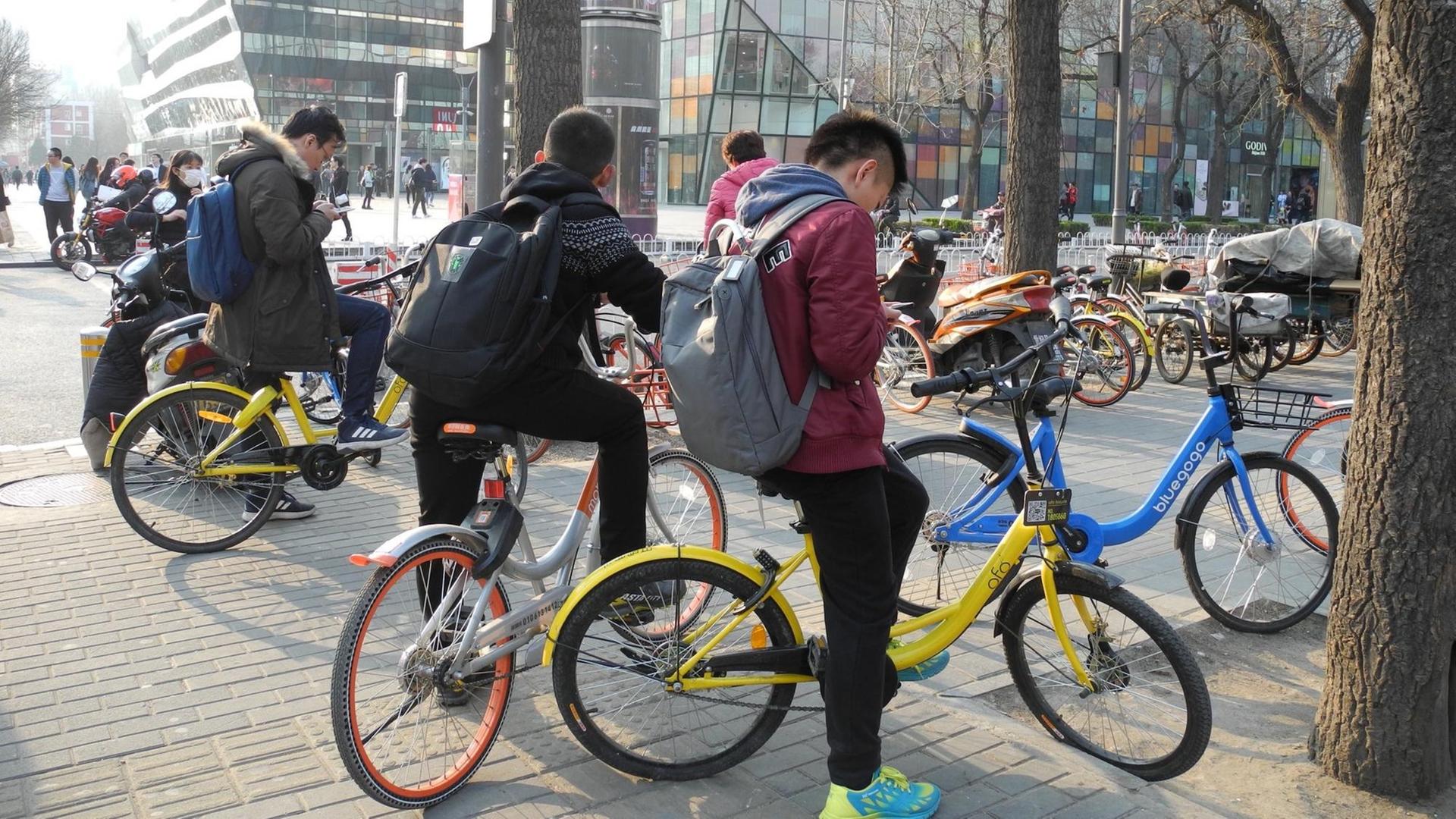 Schulkinder fahren in Peking mit Fahrrädern unterschiedlichster Anbieter.