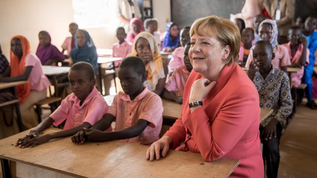 Bundeskanzlerin Merkel sitzt während ihrer Afrikareise in Niamey mit Schülern in auf einer Klassenbank. Bundeskanzlerin Merkel sitzt während ihrer Afrikareise in Niamey mit Schülern in auf einer Klassenbank.