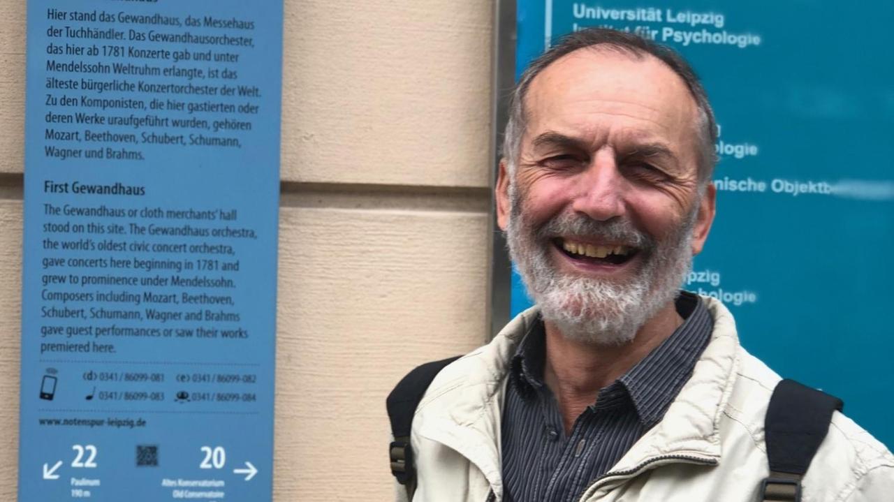 Porträt des lachenden Professors vor einer Tafel, die auf die Notenspur hinweist. Porträt des lachenden Professors vor einer Tafel, die auf die Notenspur hinweist.