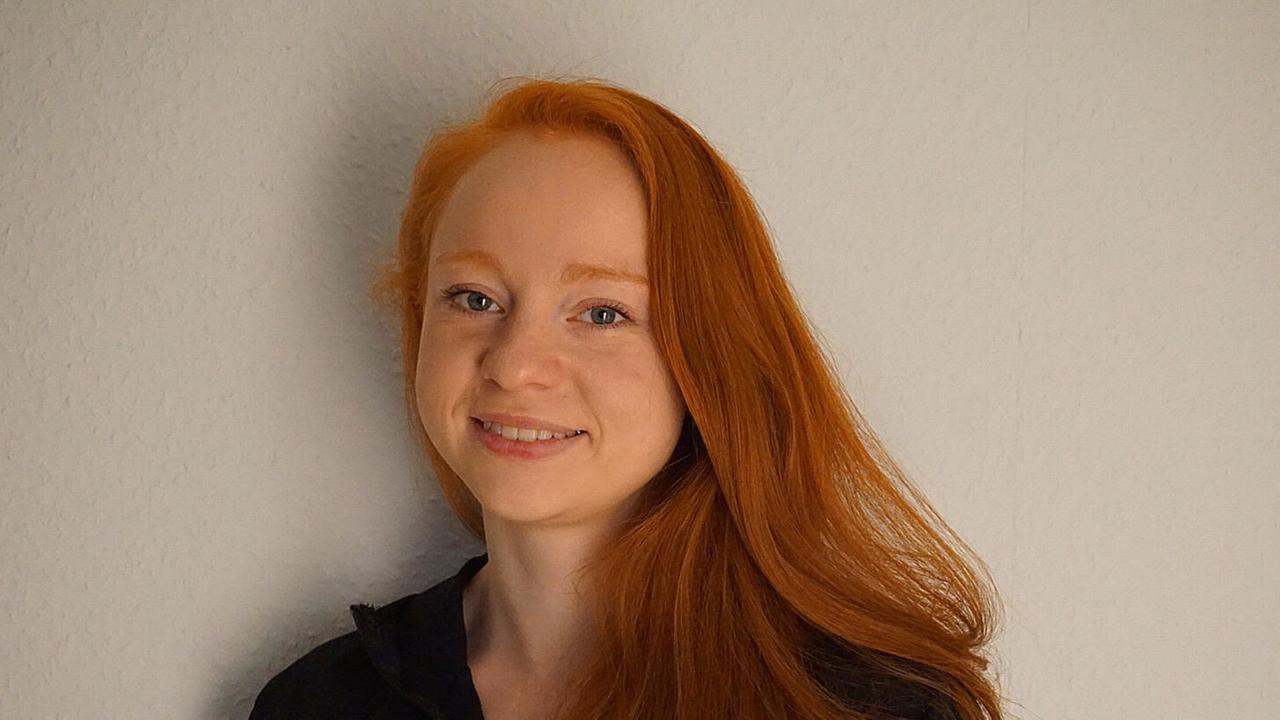 Eine Frau mit rötlichen Haaren blickt in die Kamera Eine Frau mit rötlichen Haaren blickt in die Kamera