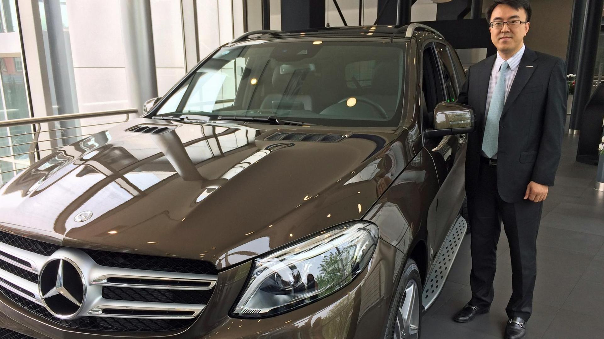 Verkaufsmanager Xu Tau neben einem SUV GLE im Mercedes-Autohaus im Pekinger Stadtbezirk Haidian