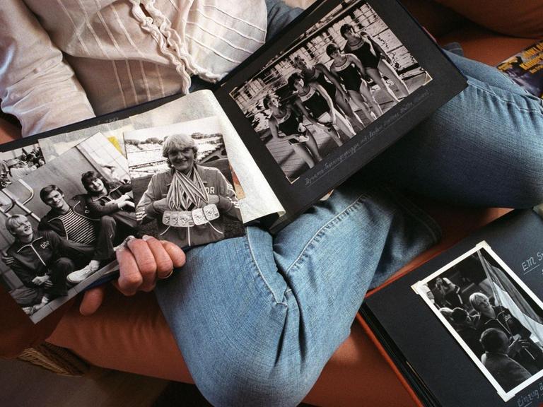 Birgit Heukrodt hält Fotos aus ihrer Zeit als DDR-Freistilschwimmerin in die Kamera.