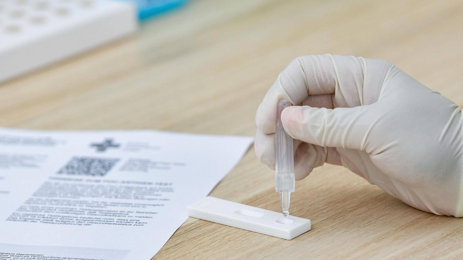 Auf eine Covid-19-Schnelltest wird eine Flüssigkeit aufgetragen. Auf eine Covid-19-Schnelltest wird eine Flüssigkeit aufgetragen.