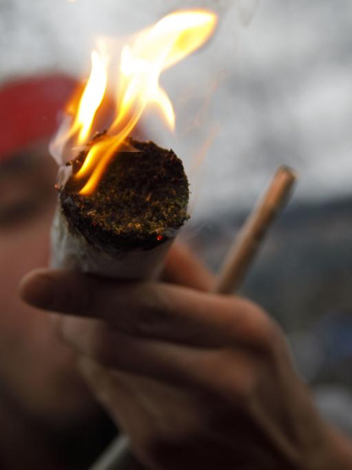 Ein Mann raucht einen riesigen Joint.