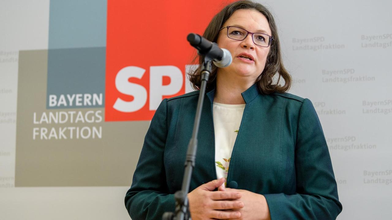 Andrea Nahles, SPD-parteivorsitzend steht mit ineinanderverschränkten Händen vor einem Mikrofon. Hinter ihr hängen Plakate mit dem SPD-Logo und eines mit der Aufschrift Bayern Landtagsfratkion.