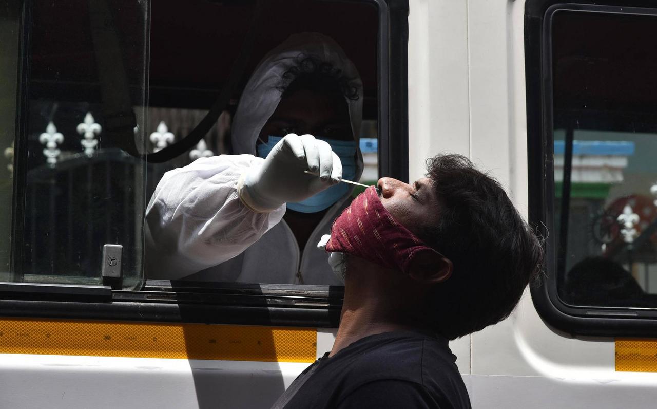 In Indien wird einem Mann mit Maske ein Abstrich aus der Nase entnommen.