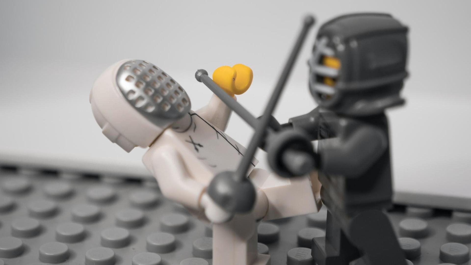 Zwei Legofiguren mit Schutzvisier fechten miteinander. Zwei Legofiguren mit Schutzvisier fechten miteinander.