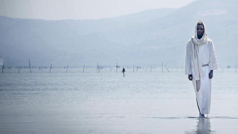 Eine Filmszene zeigt Yvan Sagnet der als schwarzer Jesus über das Wasser wandelt. Eine Filmszene zeigt Yvan Sagnet der als schwarzer Jesus über das Wasser wandelt.