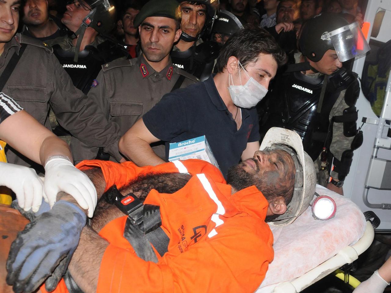 Sanitäter tragen einen verletzten Bergmann zum Krankenwagen.