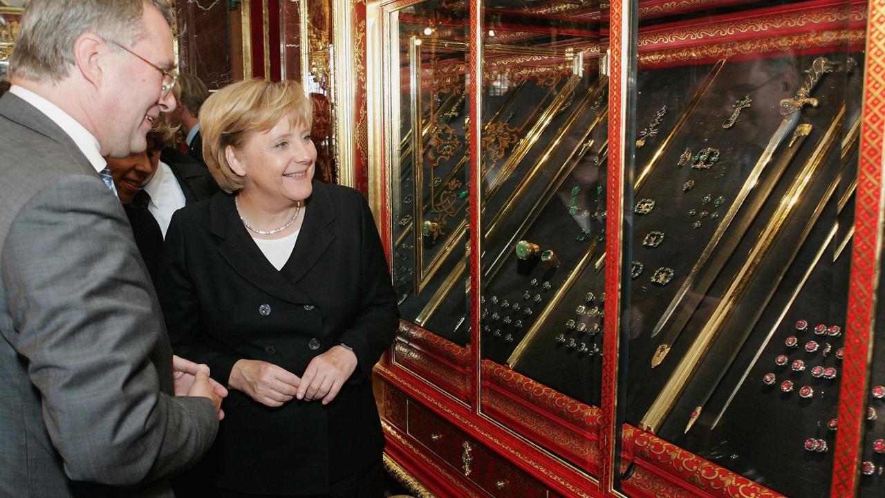 Angela Merkel und Museumsdirektor Dirk Syndram besichtigen Vitrinen mit Schmuck im Grünen Gewölbe.
