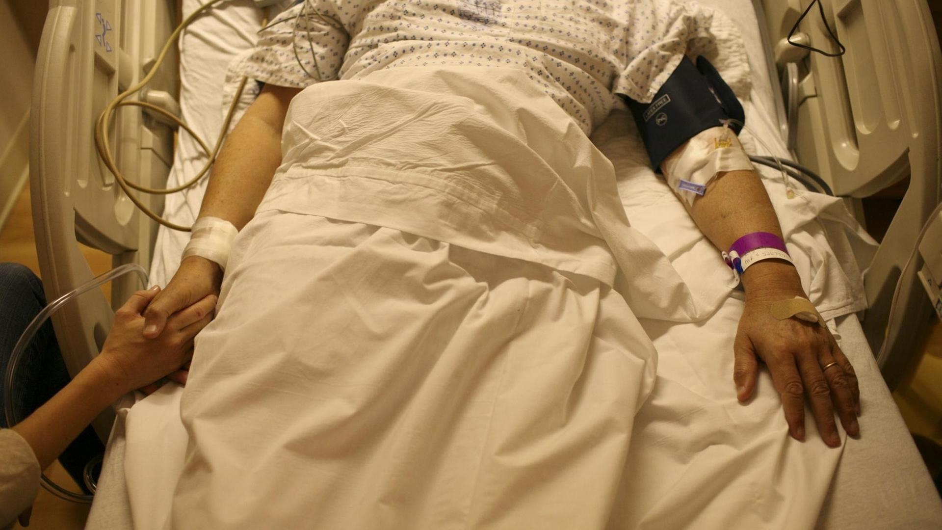 Patient in einem Krankenbett, jemand hält seine Hand Patient in einem Krankenbett, jemand hält seine Hand