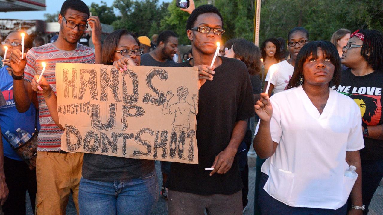 Demonstranten mit einem Transparent "Hands up - don't shoot" ("Hände hoch - nicht schießen") versammeln sich auf der West Florissant Avenue in Ferguson, Missouri, USA, am 14. August 2014.