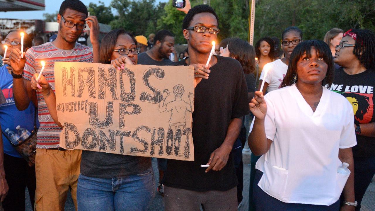 Demonstranten mit einem Transparent "Hands up - don't shoot" ("Hände hoch - nicht schießen") versammeln sich auf der West Florissant Avenue in Ferguson, Missouri, USA, am 14. August 2014. Demonstranten mit einem Transparent "Hands up - don't shoot" ("Hände hoch - nicht schießen") versammeln sich auf der West Florissant Avenue in Ferguson, Missouri, USA, am 14. August 2014.