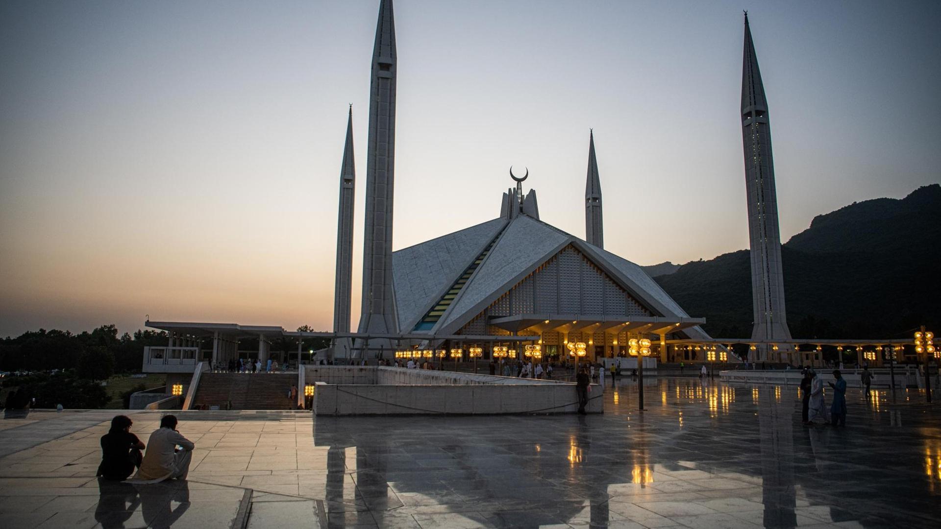 Besucher der Faisal-Moschee in der pakistanischen Hauptstadt Islamabad sitzen bei Sonnenuntergang auf dem Vorplatz der Moschee. Besucher der Faisal-Moschee in der pakistanischen Hauptstadt Islamabad sitzen bei Sonnenuntergang auf dem Vorplatz der Moschee.