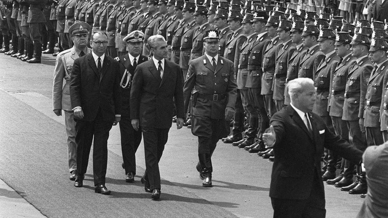 Der iranische Schah Reza Mohammed Pahlavi (M) schreitet am 2. Juni 1967 die Front der Ehrenformation der Berliner Bereitschaftspolizei mit dem Regierenden Bürgermeister Heinrich Albertz (l) auf dem Flughafen Tempelhof in Berlin ab. Das iranische Herrscherpaar hielt sich für 24 Stunden im westlichen Teil der geteilten Stadt auf. Der Besuch des Schahs löste Massendemonstrationen und schwere Tumulte gegen den iranischen Herrscher aus, der Student Benno Ohnesorg kam dabei ums Leben. Der iranische Schah Reza Mohammed Pahlavi (M) schreitet am 2. Juni 1967 die Front der Ehrenformation der Berliner Bereitschaftspolizei mit dem Regierenden Bürgermeister Heinrich Albertz (l) auf dem Flughafen Tempelhof in Berlin ab. Das iranische Herrscherpaar hielt sich für 24 Stunden im westlichen Teil der geteilten Stadt auf. Der Besuch des Schahs löste Massendemonstrationen und schwere Tumulte gegen den iranischen Herrscher aus, der Student Benno Ohnesorg kam dabei ums Leben.