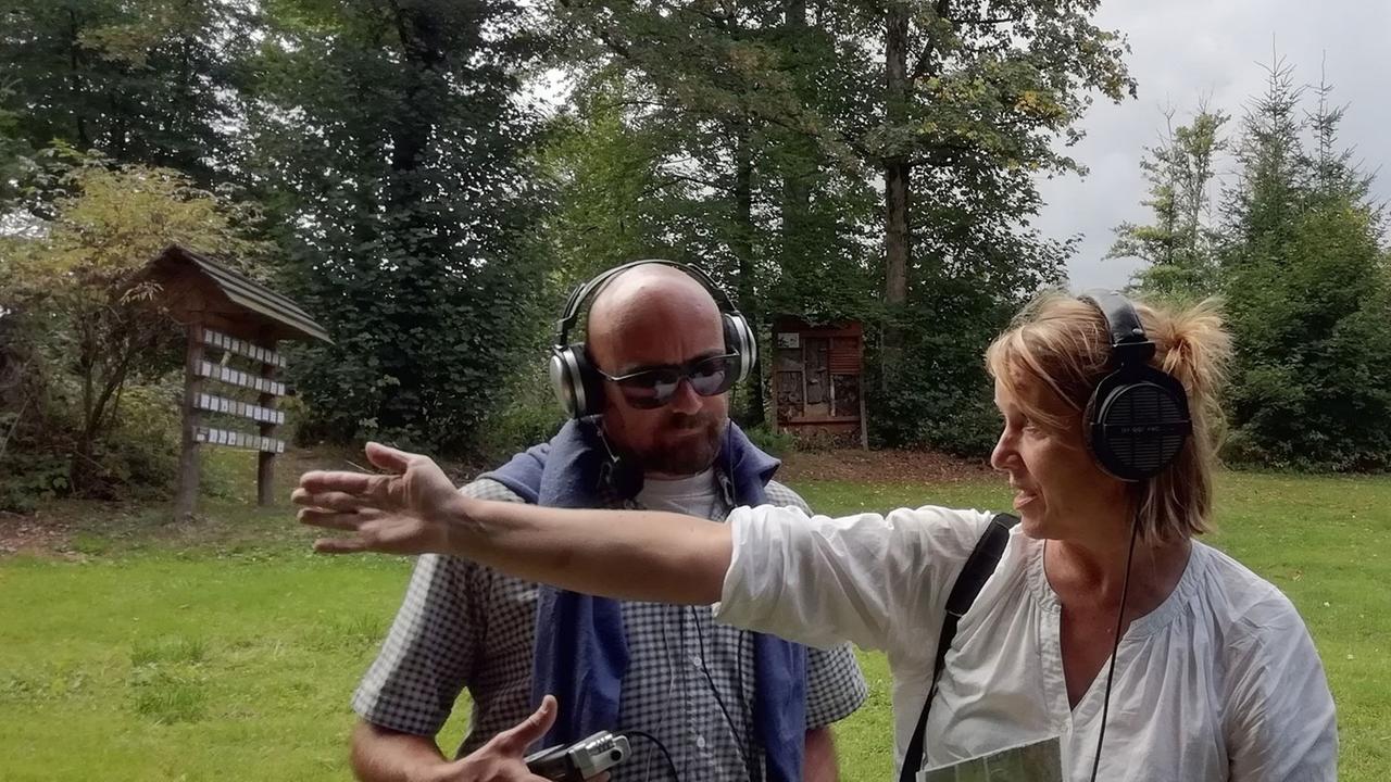 Antje Vowinckel und Mat Pogo auf einer grünen Wiese, die umgeben ist von Bäumen Antje Vowinckel und Mat Pogo auf einer grünen Wiese, die umgeben ist von Bäumen