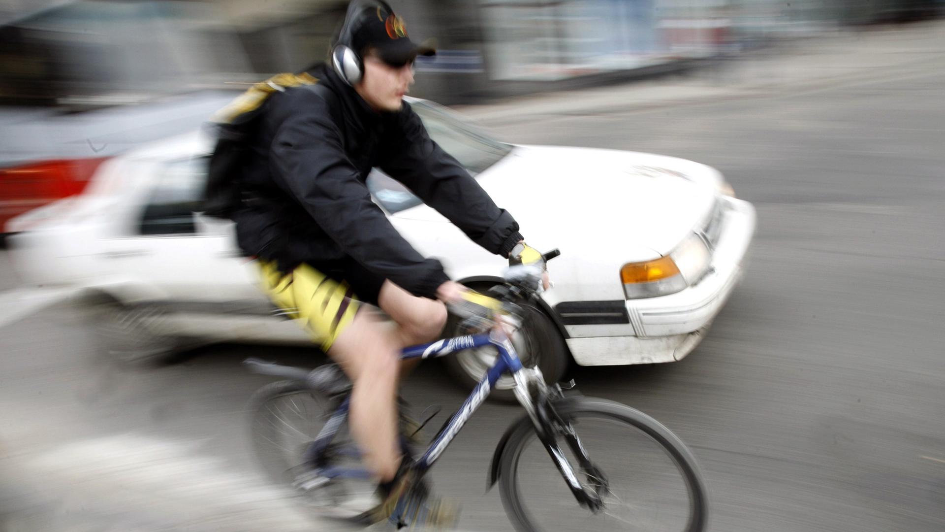 Radfahrer mit Kopfhörer im Straßenverkehr Radfahrer mit Kopfhörer im Straßenverkehr