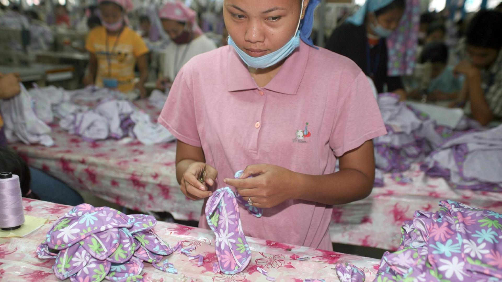 Eine junge kambodschanische Näherinnen bei der Kontrolle von Augenbinden und Pyjamas, die für den europäischen Markt gefertigt wurden, in einer Textilfabrik am Rande Phnom Penhs (Archivfoto aus dem Jahr 2007). Nach erfolglosen Streiks sind die meisten Textilarbeiterinnen in Kambodscha am 08.01.2014 wieder an ihre Arbeitsplätze zurückgekehrt. Die Textilindustrie ist mit 3,7 Milliarden Euro Exporterlösen im Jahr mit Abstand die größte Exportindustrie im Land. Foto: Arjay Stevens/dpa (zu dpa "Streik erfolglos - Textilarbeiterinnen in Kambodscha arbeiten wieder" vom 08.01.2014) | Verwendung weltweit Eine junge kambodschanische Näherinnen bei der Kontrolle von Augenbinden und Pyjamas, die für den europäischen Markt gefertigt wurden, in einer Textilfabrik am Rande Phnom Penhs (Archivfoto aus dem Jahr 2007). Nach erfolglosen Streiks sind die meisten Textilarbeiterinnen in Kambodscha am 08.01.2014 wieder an ihre Arbeitsplätze zurückgekehrt. Die Textilindustrie ist mit 3,7 Milliarden Euro Exporterlösen im Jahr mit Abstand die größte Exportindustrie im Land. Foto: Arjay Stevens/dpa (zu dpa "Streik erfolglos - Textilarbeiterinnen in Kambodscha arbeiten wieder" vom 08.01.2014) | Verwendung weltweit