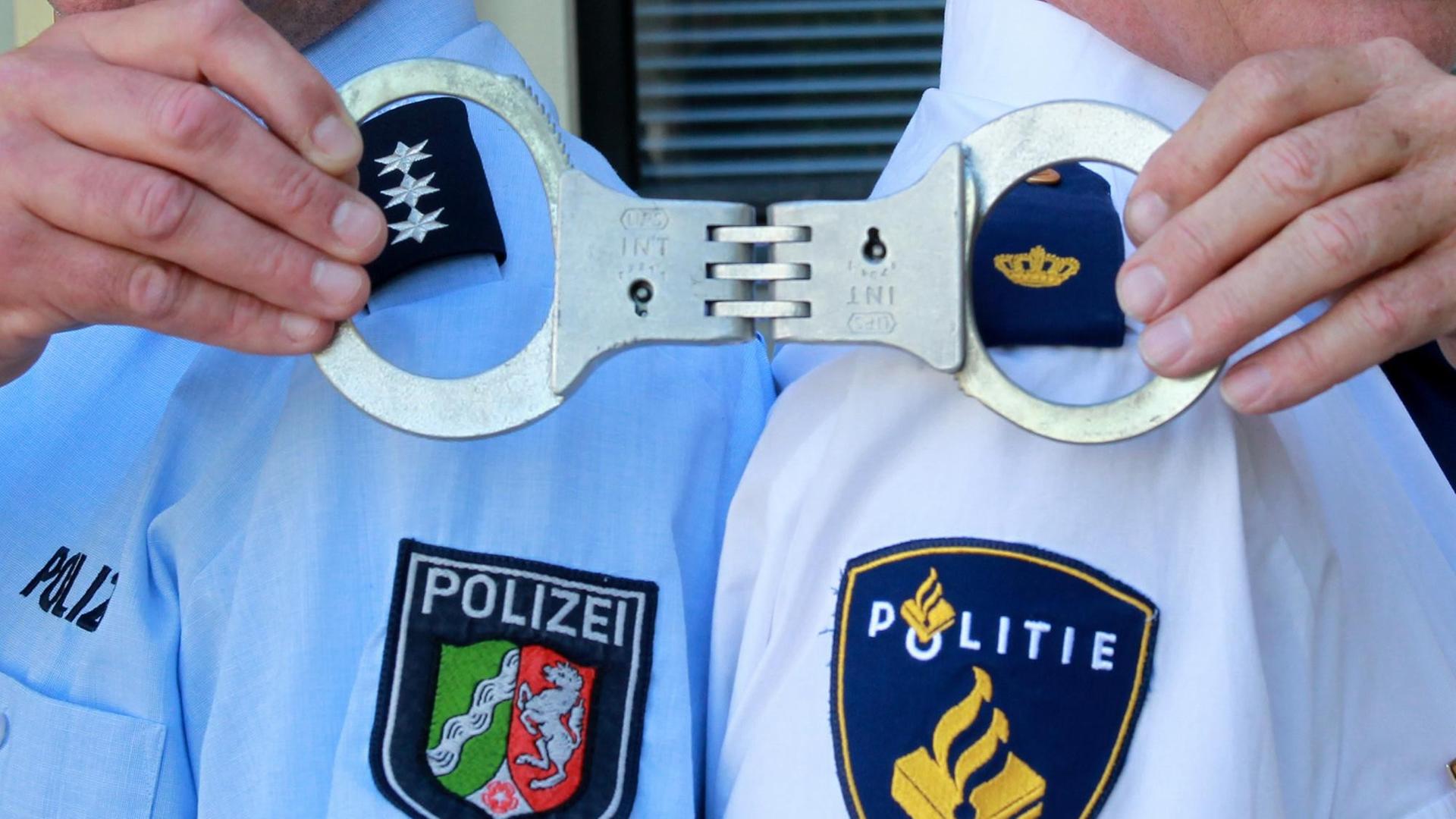 Deutsche und niederländische Polizisten posieren in einer gestellten Situation am Mittwoch (25.05.2011) in Mönchengladbach gemeinsam mit Handschellen. Staatsanwaltschaft und Polizei aus der deutsch-niederländischen Grenzregion beraten auf einer Tagung die Verbesserung in der Zusammenarbeit. Foto: Roland Weihrauch dpa/lnw | Verwendung weltweit Deutsche und niederländische Polizisten posieren in einer gestellten Situation am Mittwoch (25.05.2011) in Mönchengladbach gemeinsam mit Handschellen. Staatsanwaltschaft und Polizei aus der deutsch-niederländischen Grenzregion beraten auf einer Tagung die Verbesserung in der Zusammenarbeit. Foto: Roland Weihrauch dpa/lnw | Verwendung weltweit