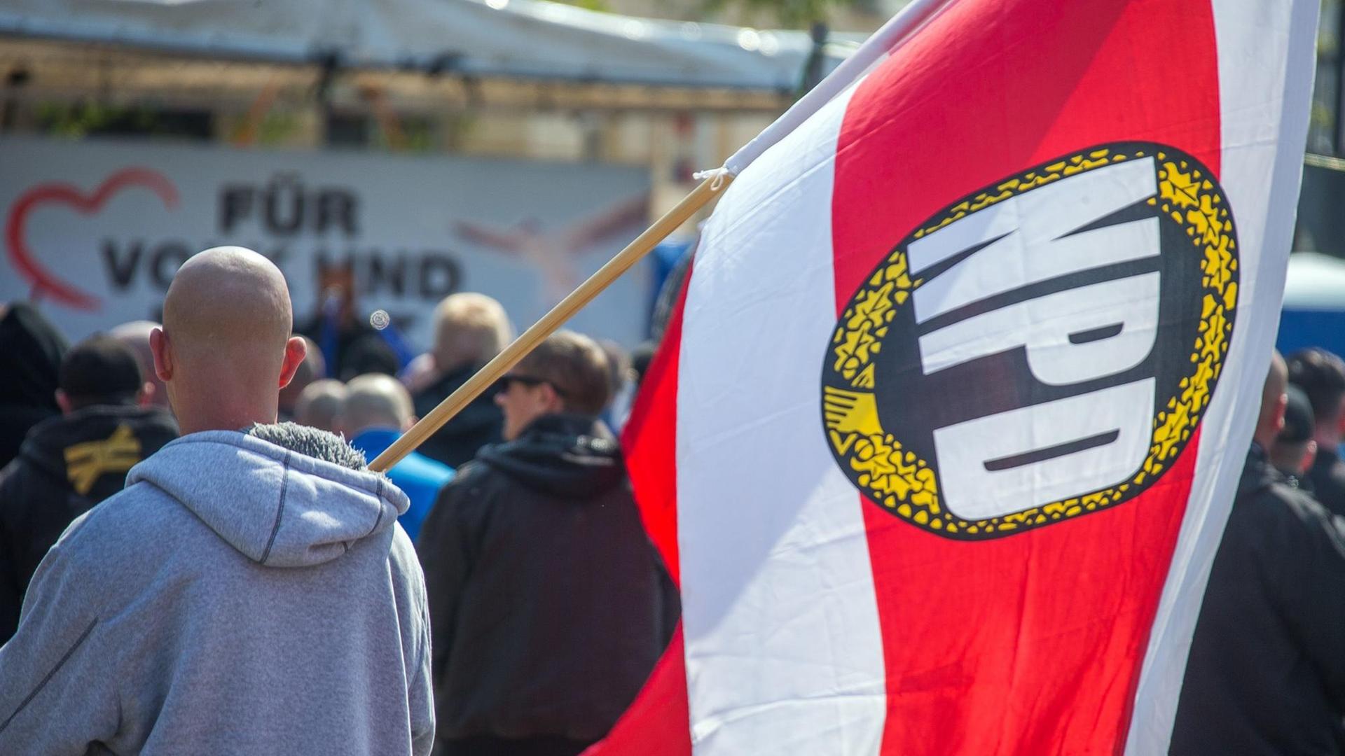 Teilnehmer einer Kundgebung der NPD am 01.05.2016 in der Innenstadt von Schwerin (Mecklenburg-Vorpommern) - einer trägt eine Fahne mit Logo der rechtsextremen Partei.
