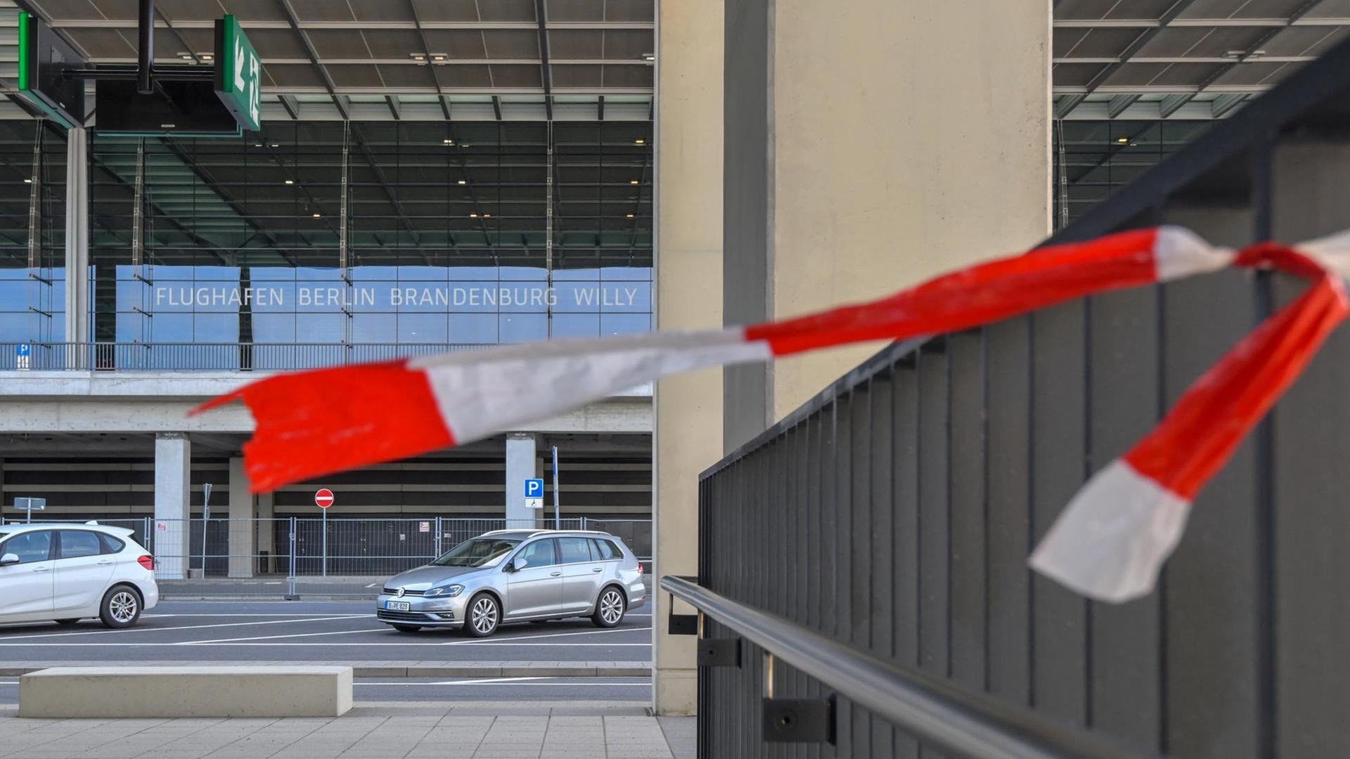 Der Rest eines Absperrbandes flattert im Wind an einem Geländer vor dem Terminal des Hauptstadtflughafens Berlin Brandenburg Willy Brandt. Der Rest eines Absperrbandes flattert im Wind an einem Geländer vor dem Terminal des Hauptstadtflughafens Berlin Brandenburg Willy Brandt.