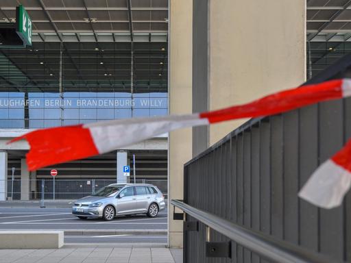 Der Rest eines Absperrbandes flattert im Wind an einem Geländer vor dem Terminal des Hauptstadtflughafens Berlin Brandenburg Willy Brandt.