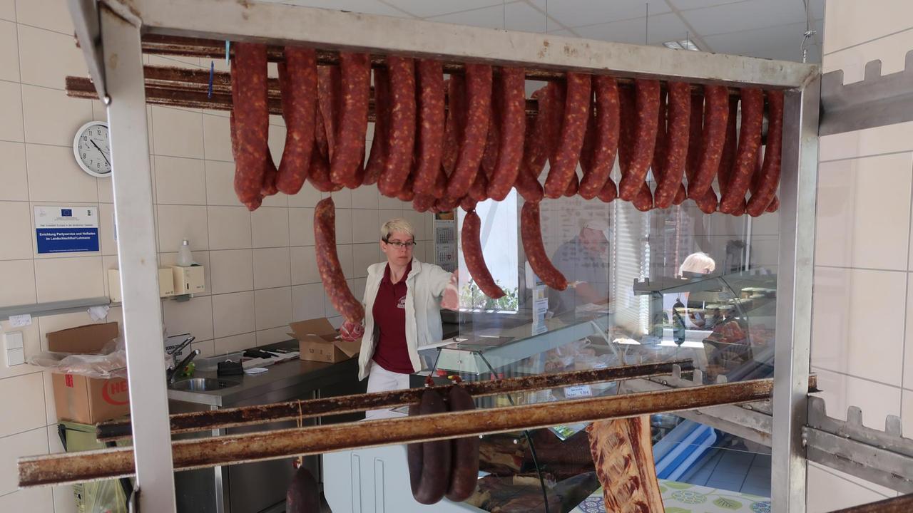 Blick in den Hofladen in dem Würste über dem Tresen hängen Blick in den Hofladen in dem Würste über dem Tresen hängen